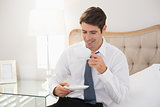 Smiling well dressed man drinking tea in bed