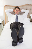Relaxed smiling well dressed man lying in bed