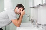 Tensed young man at washbasin in bathroom