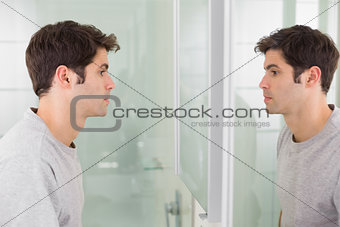 Tensed man looking at self in bathroom mirror