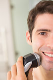 Close up of smiling man shaving with electric razor