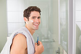 Portrait of smiling handsome man shaving in bathroom