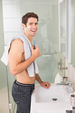 Smiling shirtless man shaving in bathroom