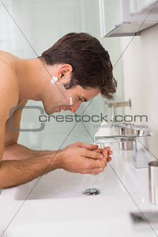 Side view of a man washing face in bathroom