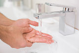 Washing hands under running water at bathroom sink