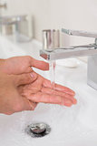 Washing hands under running water at bathroom sink