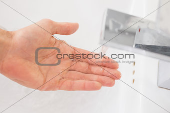Hand under running water at bathroom sink