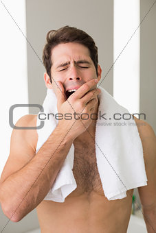 Shirtless man yawning with eyes closed at home