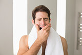 Shirtless man yawning with eyes closed at home
