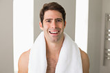 Shirtless man with towel around neck smiling at home