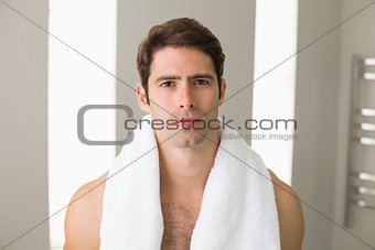 Shirtless young man with towel around neck at home