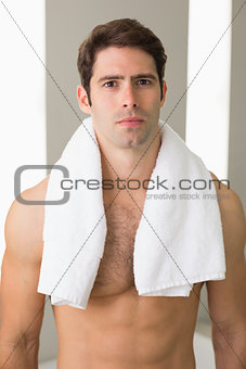 Shirtless man with towel around neck at home