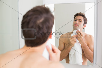 Young man looking at self in bathroom mirror