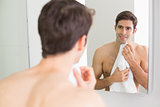 Rear view of man looking at self in bathroom mirror