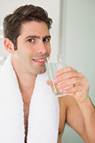 Man drinking water with towel around neck at home