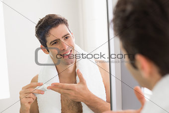 Man with reflection putting moisturizer on his face