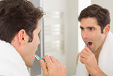 Man with reflection brushing teeth in the bathroom