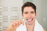 Close up portrait of man brushing teeth in bathroom