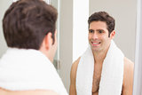 Rear view of man smiling at self in bathroom mirror