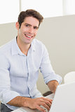 Portrait of casual smiling man using laptop at home