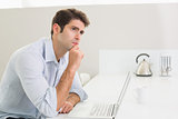 Thoughtful casual young man using laptop at home