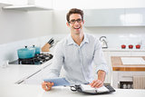 Cheerful casual man with digital tablet and diary in kitchen