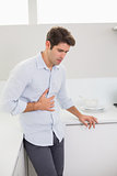 Casual man with stomach pain in the kitchen