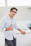 Portrait of casual man with stomach pain in kitchen