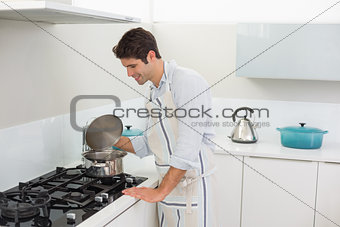 Smiling young man preparing food in the kitchen