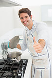 Smiling young man gesturing thumbs up in kitchen
