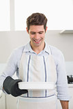 Smiling man holding a baking dish in kitchen