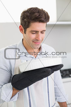 Man smelling food in baking dish in kitchen
