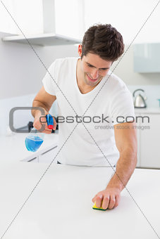 Smiling man cleaning kitchen counter in house
