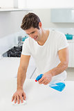 Smiling young man cleaning kitchen counter