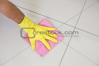Yellow gloved hand with cleaning rag wiping the floor