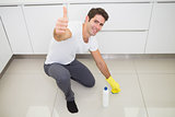 Man cleaning the kitchen floor while gesturing thumbs up