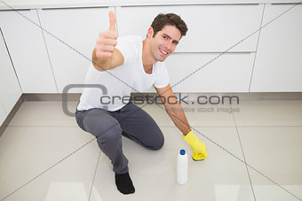 Man cleaning the kitchen floor while gesturing thumbs up