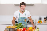 Smiling young man with vegetables standing in kitchen