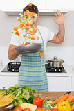 Cheerful man tossing vegetables in kitchen