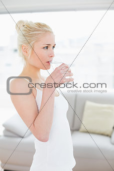 Side view of fit young woman drinking water at the gym