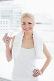 Fit smiling woman with a glass of water at gym