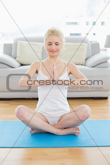 Toned woman sitting in Namaste position at fitness studio