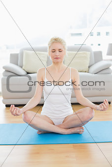 Toned woman sitting in lotus pose at fitness studio