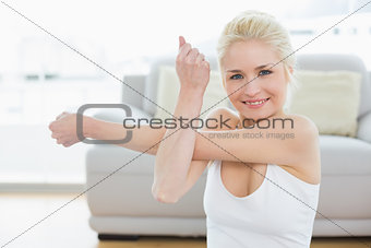 Smiling sporty woman stretching hand in fitness studio