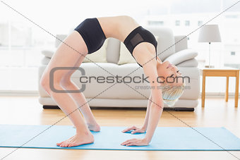 Fit woman doing the wheel pose in fitness studio