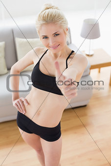 Fit woman in sportswear gesturing thumbs up at fitness studio