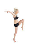 Sporty woman balancing on one leg while stretching out hands