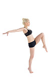 Sporty woman balancing on one leg while stretching out hands