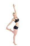 Sporty woman balancing on one leg while stretching up hand