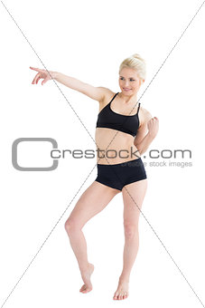 Full length of a sporty young woman pointing away